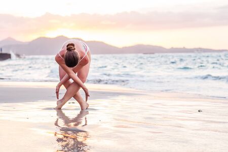 Woman practices yoga at seashoreの写真素材