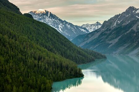 Green lake between mountains in cloudy dayの写真素材