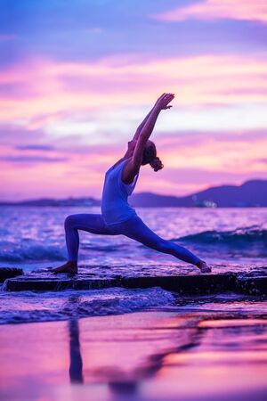 Woman practices yoga at seashoreの写真素材