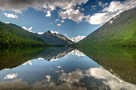 Green lake between mountains in cloudy dayの写真素材