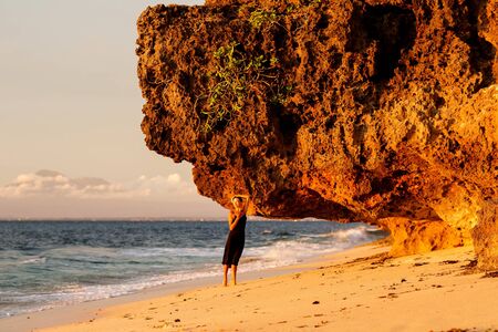 Beautiful woman by the ocean at sunsetの写真素材