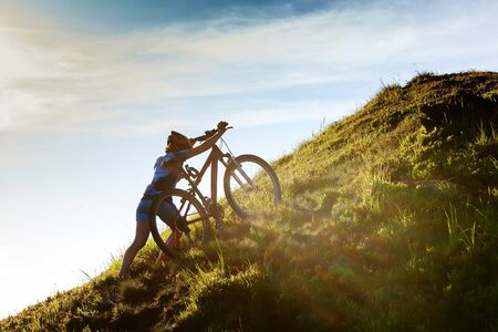 Woman rides bicycle in the beautiful green forest. Adventure, cycling.の写真素材