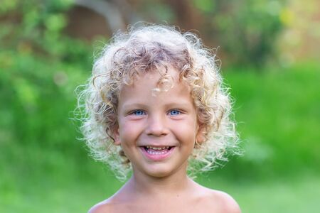 Portrait of a curly white boy in the parkの写真素材