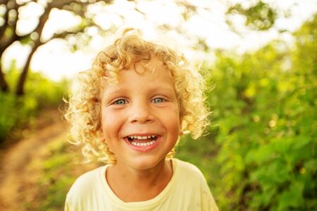 Portrait of a curly white boy in the park in sunset timeの写真素材