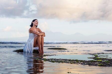 Beautiful woman by the ocean at sunsetの写真素材