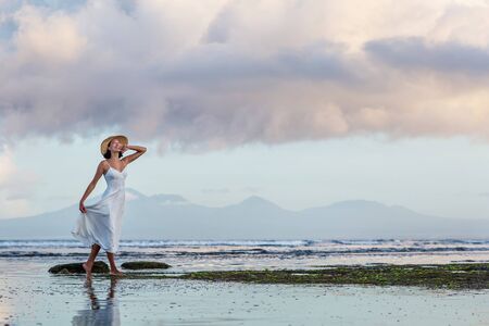 Beautiful woman by the ocean at sunsetの写真素材