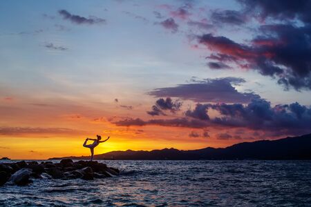 Woman practices yoga at seashoreの写真素材