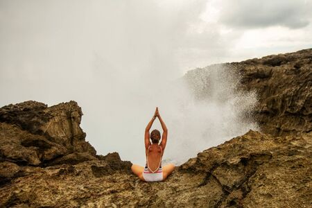 Woman practices yoga at seashoreの写真素材