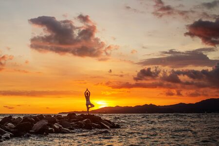 Woman practices yoga at seashoreの写真素材