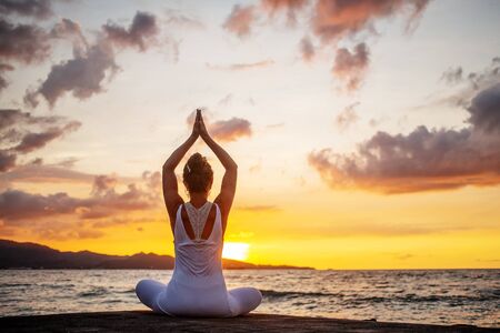 Woman practices yoga at seashoreの写真素材