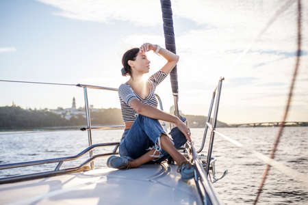 Beautiful girl resting on a yacht at sunsetの写真素材