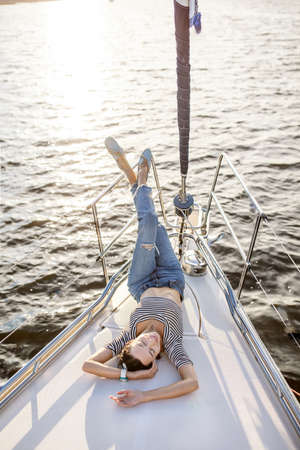 Beautiful girl resting on a yacht at sunsetの写真素材