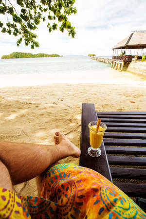 Man drinks mango juice on the beachの写真素材