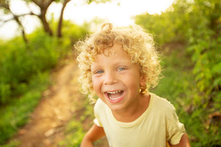 Portrait of a curly white boy in the park in sunset timeの写真素材