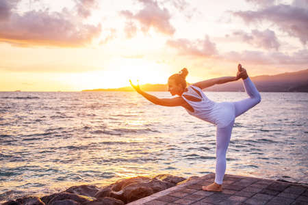 Woman practices yoga at seashoreの写真素材