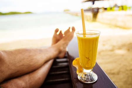 Man drinks mango juice on the beachの写真素材