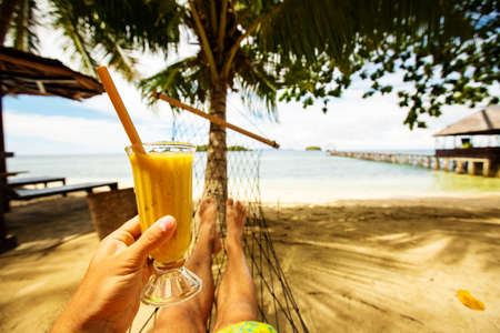Man drinks mango juice on the beachの写真素材
