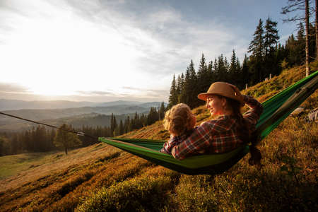 Boy tourist resting in a hammock in the mountains at sunsetの写真素材