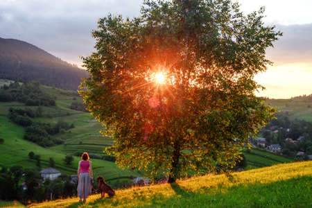 woman and dog in mountains at sunsetの写真素材