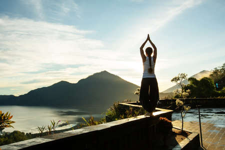 Woman doing yoga at dawn near a volcano on the island of Baliの写真素材