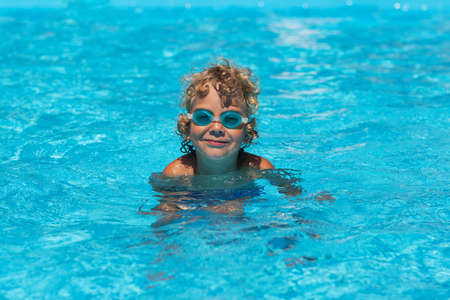 Curly boy in the pool with glassesの写真素材