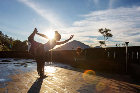 Woman doing yoga at dawn near a volcano on the island of Baliの写真素材