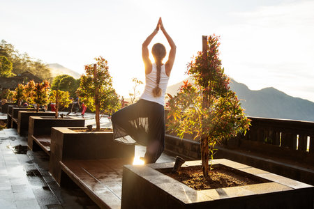 Woman doing yoga at dawn near a volcano on the island of Baliの写真素材
