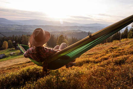 Woman hiker resting after climbing in a hammock at sunsetの写真素材