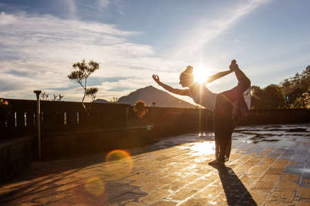 Woman doing yoga at dawn near a volcano on the island of Baliの写真素材