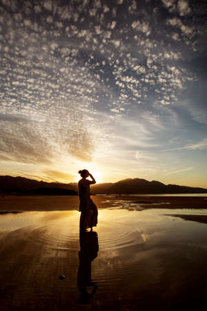 Beautiful woman dancing by the sea at sunsetの写真素材