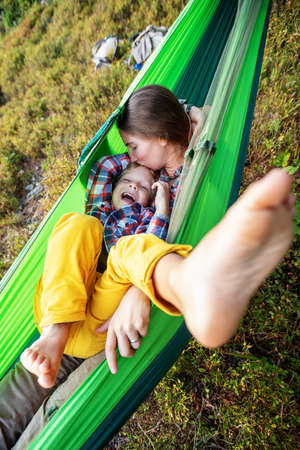 Boy with mom resting in a hammock in the mountains at sunsetの写真素材