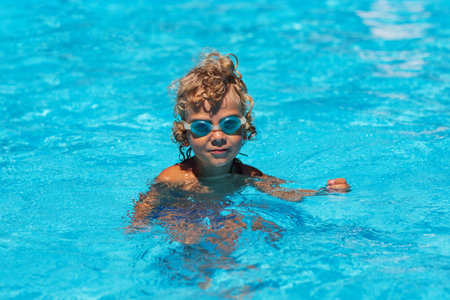 Curly boy in the pool with glassesの写真素材