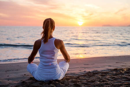 Beautiful woman doing yoga by the seaの写真素材