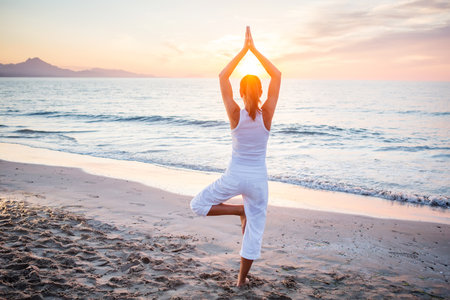 Beautiful woman doing yoga by the seaの写真素材