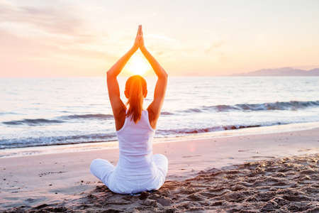 Beautiful woman doing yoga by the seaの写真素材