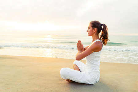 Beautiful woman doing yoga by the seaの写真素材