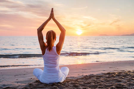 Beautiful woman doing yoga by the seaの写真素材