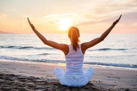Beautiful woman doing yoga by the seaの写真素材