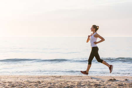 Beautiful woman running by the seaの写真素材