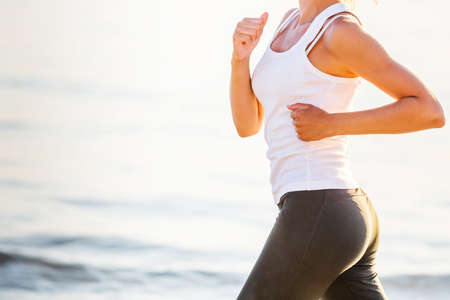 Beautiful woman running by the seaの写真素材