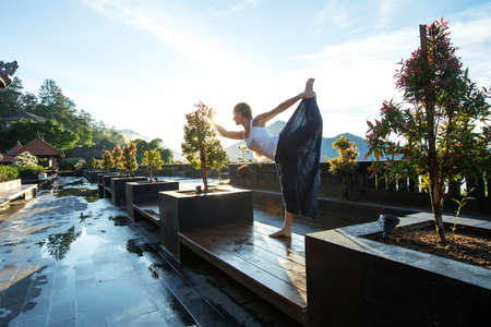 Woman doing yoga at dawn near a volcano on the island of Baliの写真素材