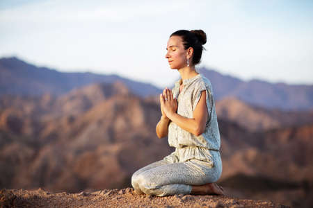 Woman practicing yoga in the mountains in the desertの写真素材