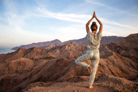 Woman practicing yoga in the mountains in the desertの写真素材