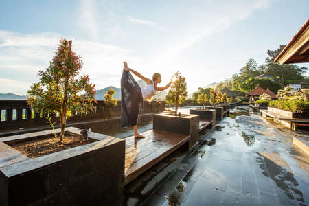 Woman doing yoga at dawn near a volcano on the island of Baliの写真素材