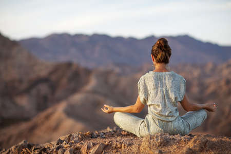 Woman practicing yoga in the mountains in the desertの写真素材