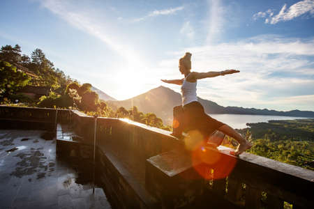 Woman doing yoga at dawn near a volcano on the island of Baliの写真素材