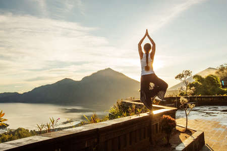 Woman doing yoga at dawn near a volcano on the island of Baliの写真素材