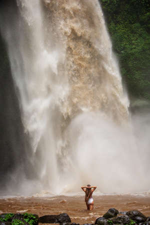 Beautiful woman near a waterfall in Baliの写真素材