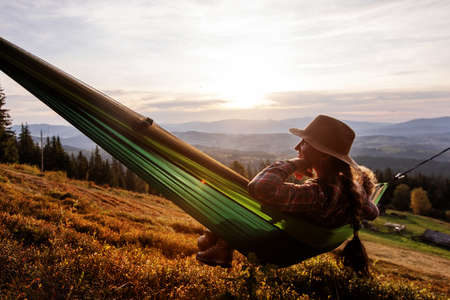 Woman hiker resting after climbing in a hammock at sunsetの写真素材