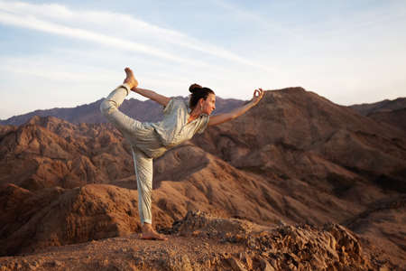 Woman practicing yoga in the mountains in the desertの写真素材